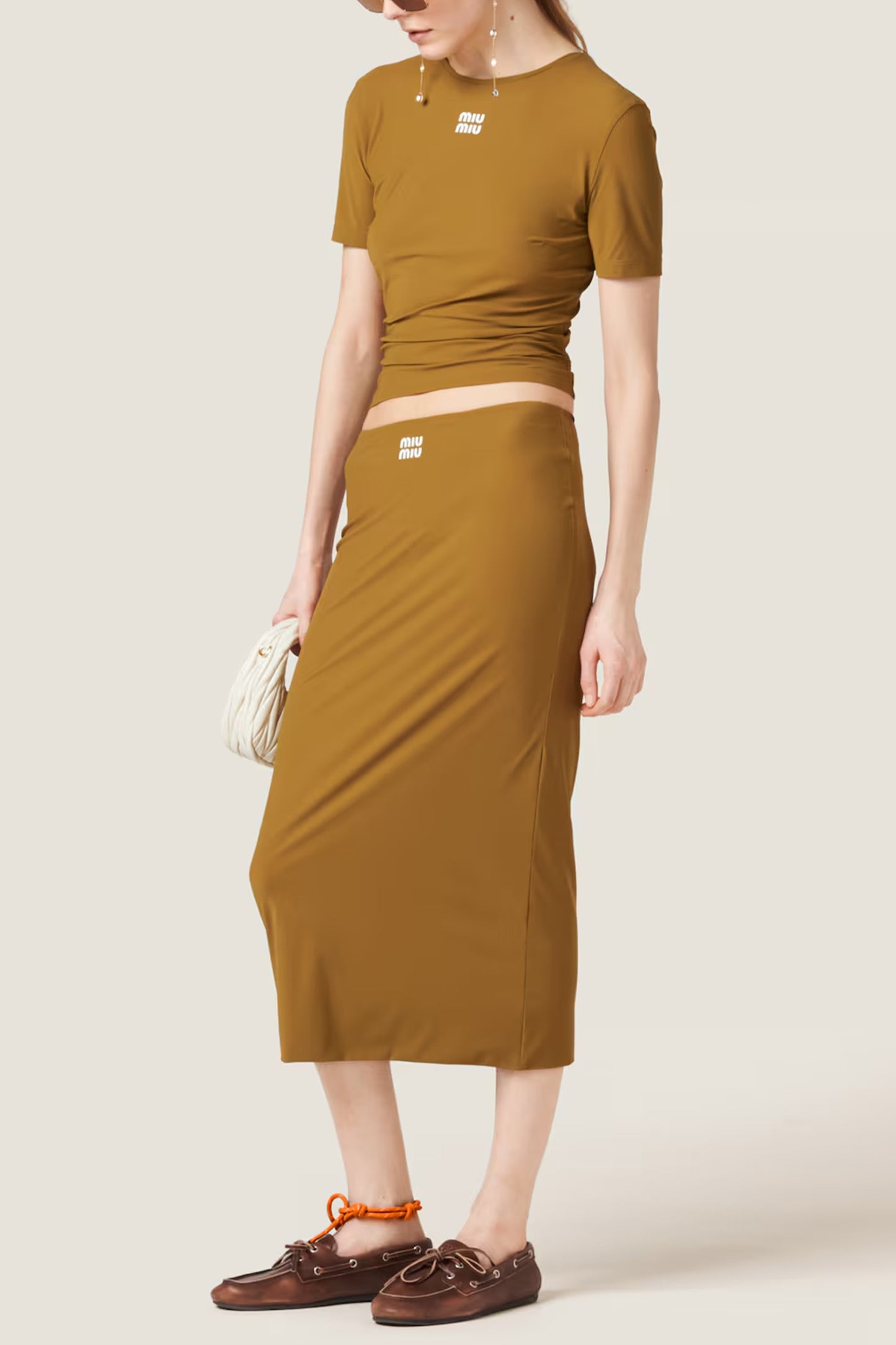 Person wearing a brown top and pencil skirt set on a white background