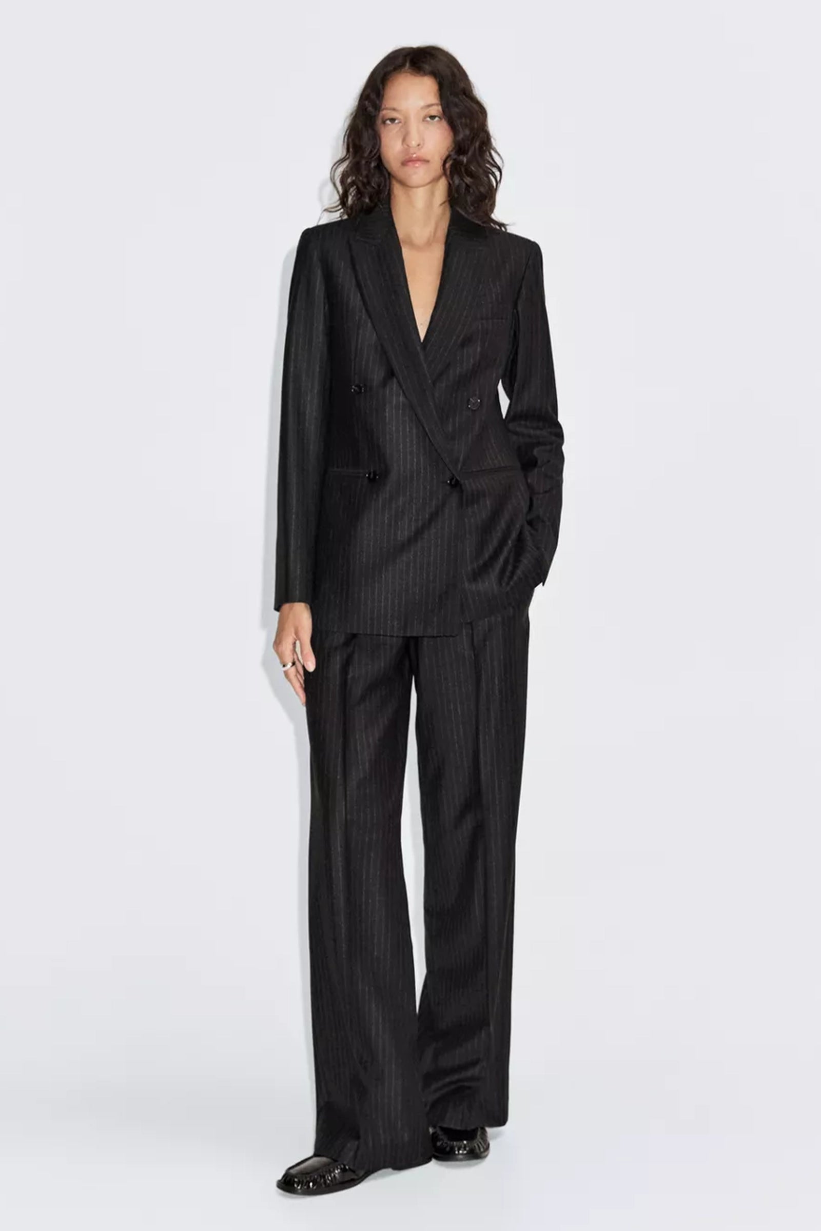 Woman wearing a black pinstripe suit on a white background
